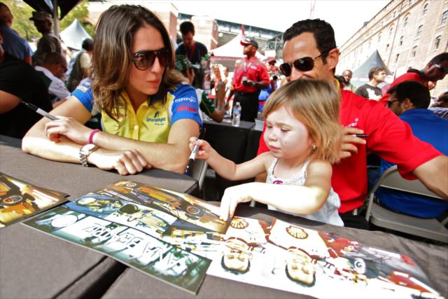 Helio Castroneves and Ana Beatriz sign autographs with a young fan -- Photo by: Shawn Gritzmacher
