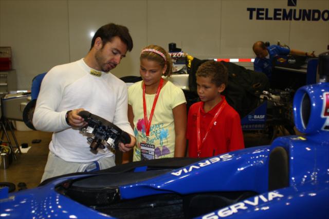 Oriol Servia showing the steering wheel from his car to young fans -- Photo by: Chris Jones