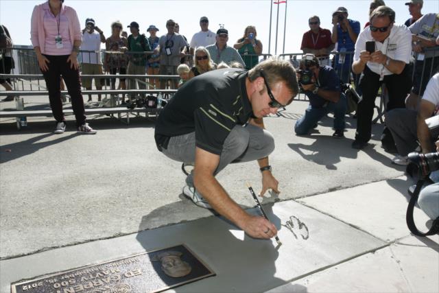 Ed Carpenter signs his name in concrete as the 2012 race winner at Auto Club Speedway -- Photo by: Richard Dowdy