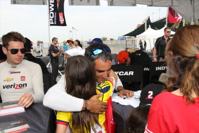 Juan Pablo Montoya receives a hug from a young fan during the autograph session in the INDYCAR Fan Village at Auto Club Speedway -- Photo by: Richard Dowdy