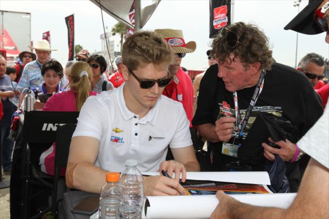 Josef Newgarden signs an autograph during the autograph session in the INDYCAR Fan Village at Auto Club Speedway -- Photo by: Richard Dowdy