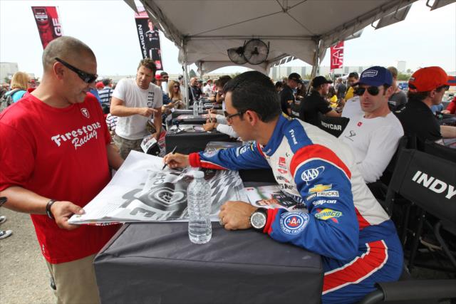 Helio Castroneves signs an autograph during the autograph session in the INDYCAR Fan Village at Auto Club Speedway -- Photo by: Richard Dowdy