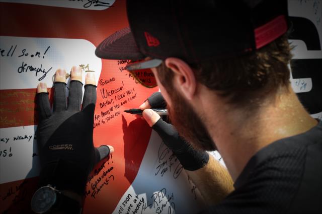 James Hinchcliffe signs the #GetWellWickens banner for his friend Robert Wickens during the autograph session at Gateway Motorsports Park -- Photo by: Shawn Gritzmacher