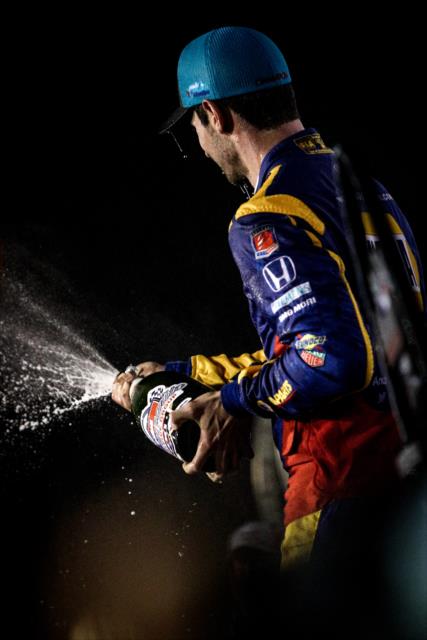 Alexander Rossi sprays the champagne on stage following the Bommarito Automotive Group 500 at Gateway Motorsports Park -- Photo by: Shawn Gritzmacher