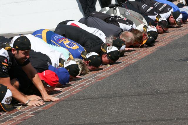 Alexander Rossi kisses the bricks with his team after winning the 100th Running of the Indianapolis 500 presented by PennGrade Motor Oil -- Photo by: Joe Skibinski