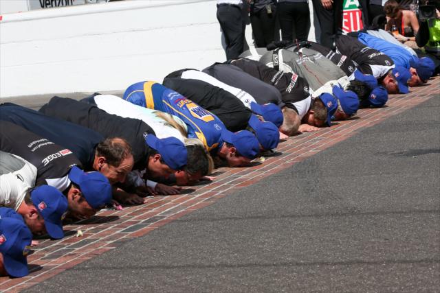 Alexander Rossi kisses the bricks with his team after winning the 100th Running of the Indianapolis 500 presented by PennGrade Motor Oil -- Photo by: Joe Skibinski
