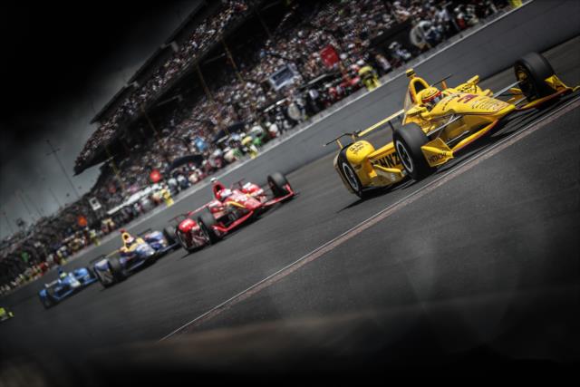 Helio Castroneves leads a group down the frontstretch during the 100th Indianapolis 500 -- Photo by: Shawn Gritzmacher