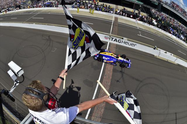 Alexander Rossi takes the twin checkers to win the 100th Indianapolis 500 -- Photo by: Walter Kuhn