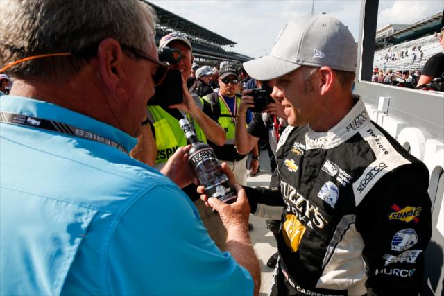 Ed Carpenter is presented a bottle of Fuzzy's Vodka on pit lane by Fuzzy Zoeller after winning the pole position for the 102nd Indianapolis 500 at the Indianapolis Motor Speedway -- Photo by: Joe Skibinski