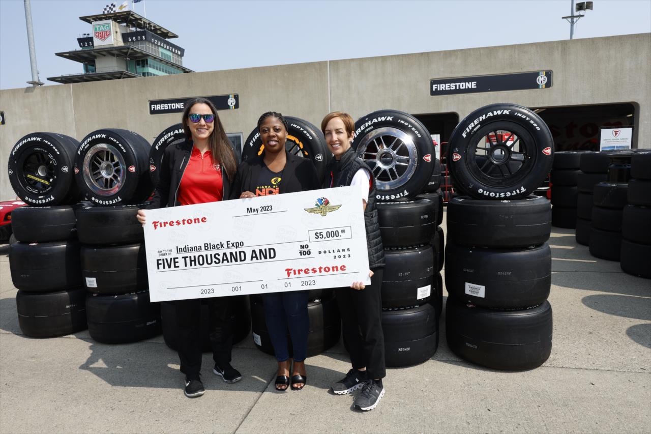 Firestone's Cara Krstolic and Lisa Boggs present a check to the Indian Black Expo - Indianapolis 500 Practice - By: Chris Jones -- Photo by: Chris Jones