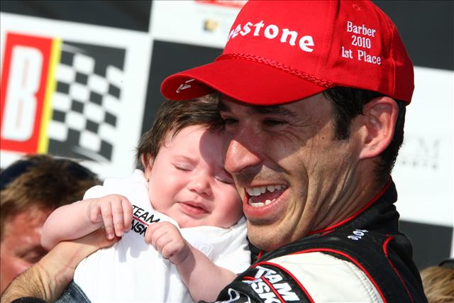 Helio celebrates with his newborn baby after his win at the inaugural race at Barber Motorsports Park. -- Photo by: Dan Helrigel