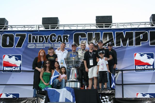 Friends and family crowd around race and series champion, Dario Franchitti. -- Photo by: Chris Jones