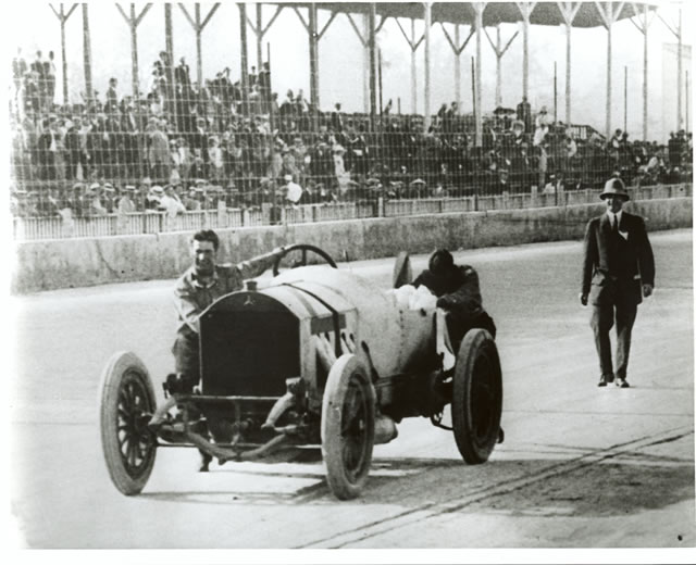 After leading 196 laps of the 1912 Indianapolis 500-Mile Race, the Mercedes of Ralph DePalma (left) and mechanic Rupert Jeffkins broke down on the backstretch just two laps from victory. The two are seen here pushing the massive car toward the finish line, the crowd roaring with applause. They finished 11th. DePalma would win the 1915 