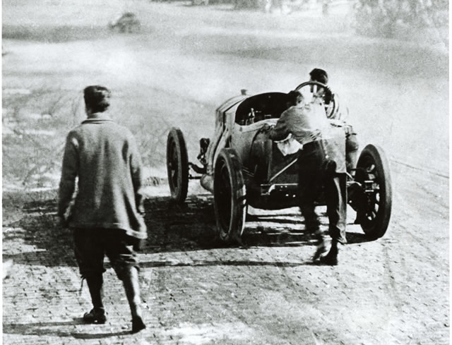 Ralph DePalma, #4, Mercedes, Mercedes, Mercedes and his riding mechanic, Rupert Jeffkins push his car to the pits. -- Photo by: No Photographer