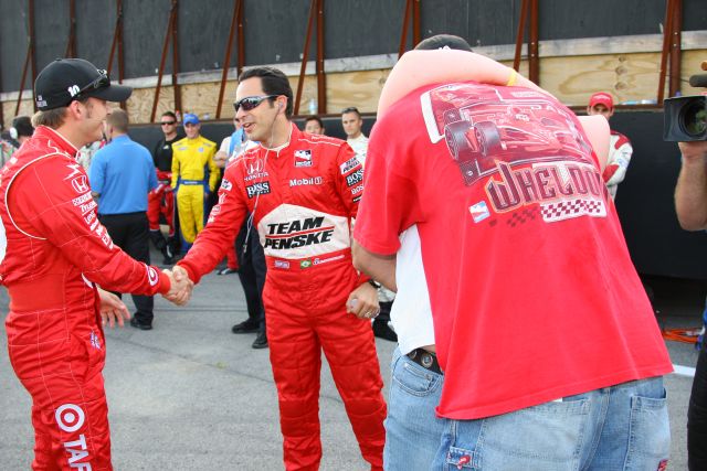 Dan Wheldon and Helio Castroneves thank each other for a job well done after helping a man propose to his girlfriend at the Kentucky Speedway on race day. -- Photo by: Shawn Payne