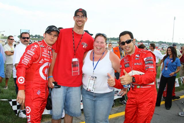 Dan Wheldon and Helio Castroneves pose for pictures after helping a man propose to his girlfriend at the Kentucky Speedway on race day. -- Photo by: Shawn Payne