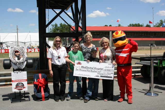 CARA Charities gives a check to MedCentral Hospital before the Honda 200 at Mid-Ohio. -- Photo by: Chris Jones