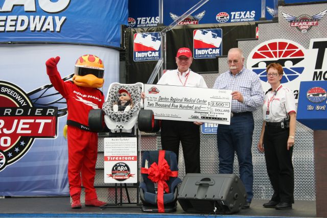 Denton Regional Medical Center gets a check from CARA Charities at Texas Motor Speedway before the Bombardier Learjet 550k. -- Photo by: Chris Jones