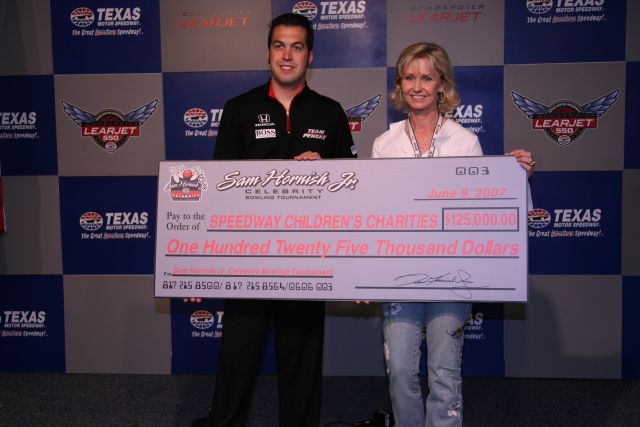 Sam Hornish Jr. gives a check to the Speedway Children's Charities from the money he raised during his celebrity bowling touramnet. -- Photo by: Shawn Payne
