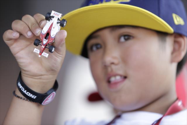 A young fan shows off his Takuma Sato 1:64 scale car during the autograph session in the INDYCAR Fan Village at Sonoma Raceway -- Photo by: Shawn Gritzmacher