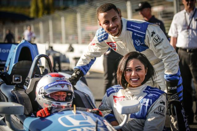 Grand Marshal Ayesha Curry poses with her husband, Steph Curry, and INDYCAR Legend Mario Andretti prior to her two-seater ride around Sonoma Raceway -- Photo by: Shawn Gritzmacher