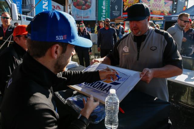 Ed Jones signs a poster for a fan during the autograph session in the INDYCAR Fan Village at Sonoma Raceway -- Photo by: Joe Skibinski