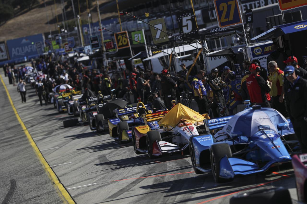 Indy cars and their teams lined up on pit lane -- Photo by: Chris Owens