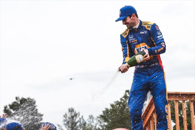 Alexander Rossi sprays the champagne over his team in Victory Circle after winning the Honda Indy 200 at Mid-Ohio -- Photo by: Joe Skibinski