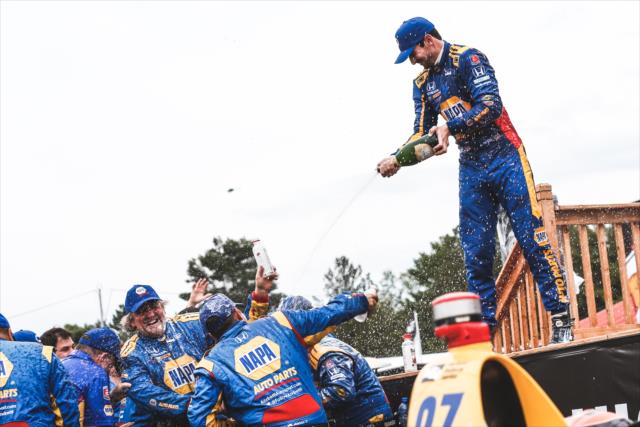 Alexander Rossi gives his Andretti Autosport team a champagne shower in Victory Circle after winning the Honda Indy 200 at Mid-Ohio -- Photo by: Joe Skibinski