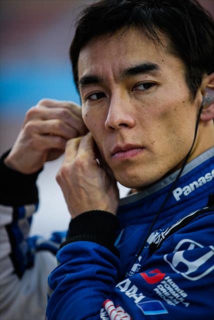 Takuma Sato sets his earpieces along pit lane prior to the evening open test session at ISM Raceway -- Photo by: Shawn Gritzmacher