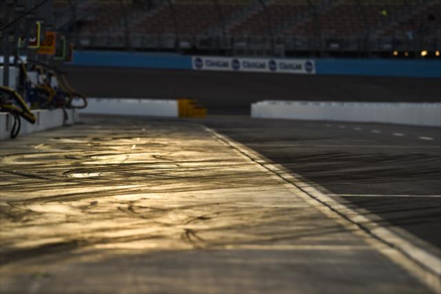 Pit lane shows the scars of tire tracks during the evening test session at ISM Raceway -- Photo by: Chris Owens