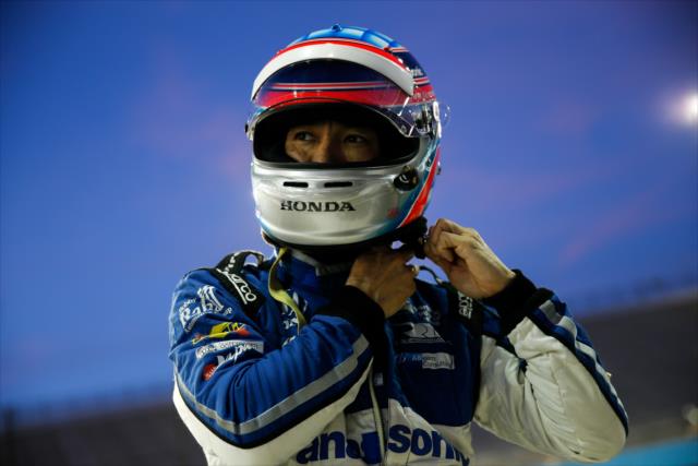 Takuma Sato straps on his helmet along pit lane during the evening open test session at ISM Raceway -- Photo by: Joe Skibinski