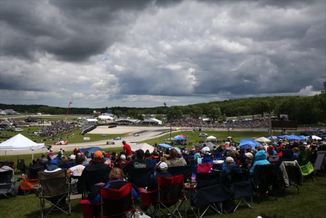 The field streams out of Turn 5 in front of the packed crowd during the KOHLER Grand Prix at Road America -- Photo by: Chris Jones
