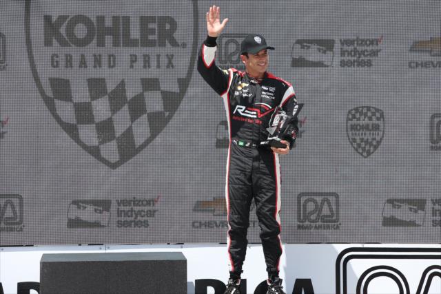 Helio Castroneves waives to the crowd after accepting his 3rd Place trophy in Victory Circle for the KOHLER Grand Prix at Road America -- Photo by: Chris Jones