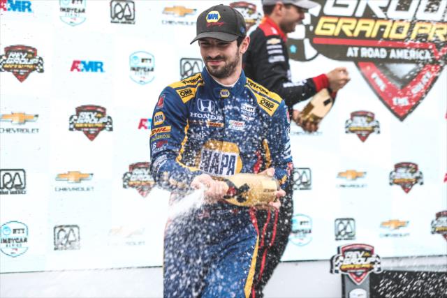 Alexander Rossi with Champagne on the podium after winning the REV Group Grand Prix at Road America -- Photo by: Joe Skibinski