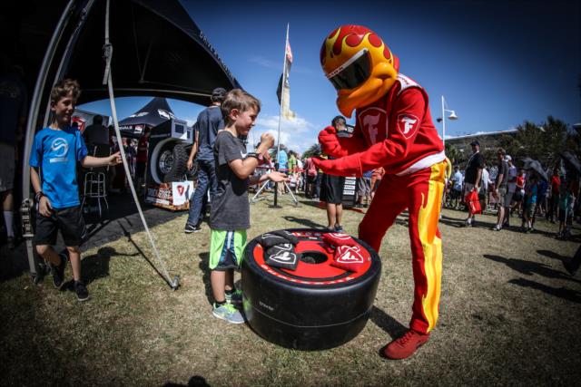 The Firestone Firehawk plays rock-paper-scissors with a youngster in the St. Petersburg Fan Village -- Photo by: Shawn Gritzmacher