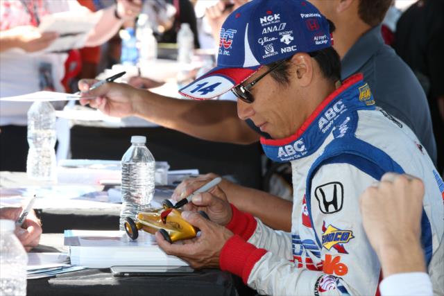 Takuma Sato signs an open-wheel roadster model during the autograph session in the INDYCAR Fan Village at Watkins Glen International -- Photo by: Chris Jones
